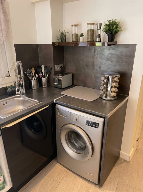 Kitchenette compacte de l'appartement Le Saint Brice de Paris avec lave-linge, cuisinière, évier et rangements organisés