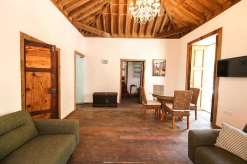 Amplia sala de estar en Casa 1820, apartamento rural en La Palma con vigas de madera, sofás, mesa de comedor y vistas al jardín