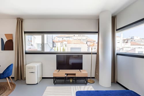 Moderno estúdio em Porto com TV, kitchenette, poltrona azul e vista para a cidade