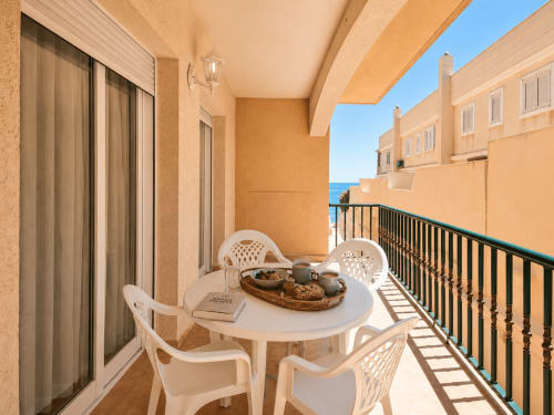 Balcón soleado con mobiliario blanco y vistas al mar en Apartamentos El Calón Playa, Cuevas del Almanzora
