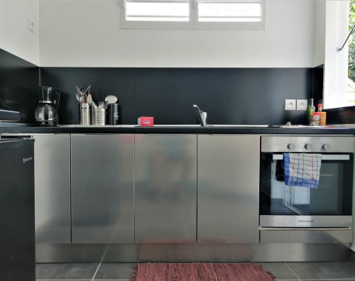 Cuisine moderne avec électroménagers en acier inoxydable et dosseret sombre au gîte Kaz A Bibi à Sainte-Rose, Guadeloupe