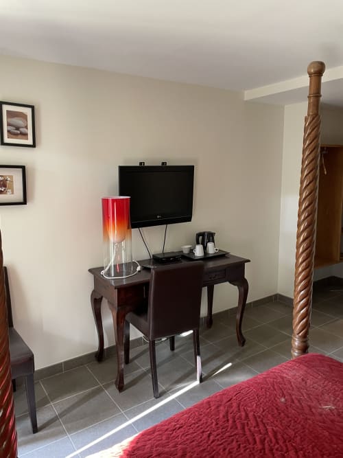 Chambre aux Pratges à Figeac avec lit rouge, meuble en bois, TV et bureau