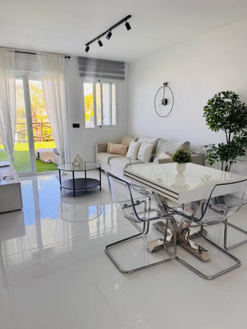 Salón moderno con vista al mar, zona de comedor, sofá beige, muebles de cristal y acceso a terraza en ALTOVELOO MAR