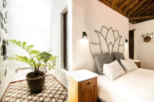 Dormitorio moderno en Casa 1820 con cabecera de metal con forma de loto, ropa de cama blanca, mesita de madera y helecho en maceta