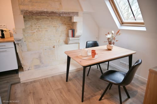 Modern dining area in Marianne Apartment at Villa République Normandie, Caen, with wooden table, black chairs, fireplace, and