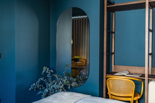 Quarto studio moderno em hotel no Porto com paredes turquesas, espelho oval, cadeira amarela e cama elegante