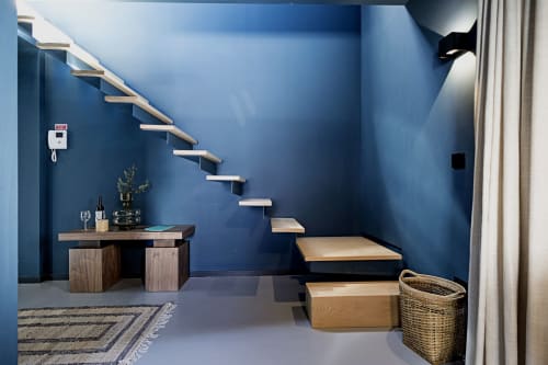 Studio duplex moderno no hotel Porto com escadas flutuantes de madeira, paredes azuis, área de trabalho e cesto de armazenamento trançado