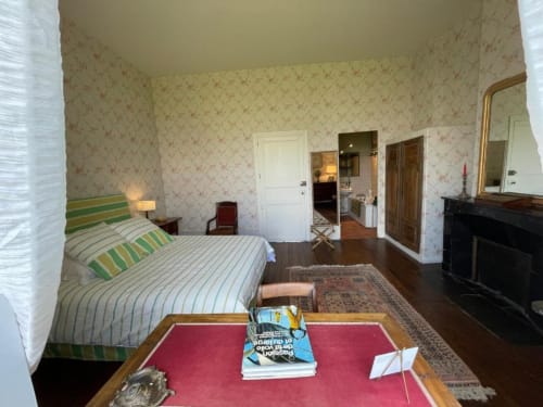 Chambre élégante au Château de Vaux Morvan avec literie rayée, papier peint fleuri, cheminée et vue sur le jardin