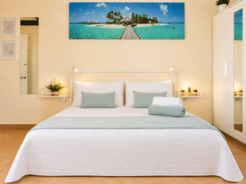 Chambre lumineuse à la Casa de Carlo, Corralejo, avec tableau de plage tropicale turquoise au-dessus du lit blanc avec vue sur mer