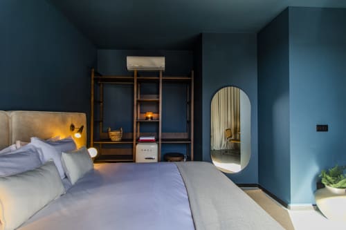 Quarto moderno no hotel Porto com paredes azuis, guarda-roupa de madeira, cama com luminárias de leitura, espelho oval e vista para o jardim