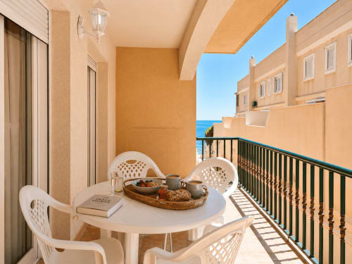 Balcón frente al mar en Apartamentos El Calón Playa con muebles blancos, desayuno y vistas al océano