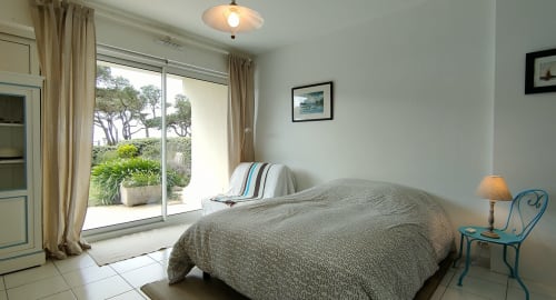Chambre lumineuse à Mer et Maisons avec vue mer, lit, fauteuil turquoise et accès patio à La Trinité sur Mer