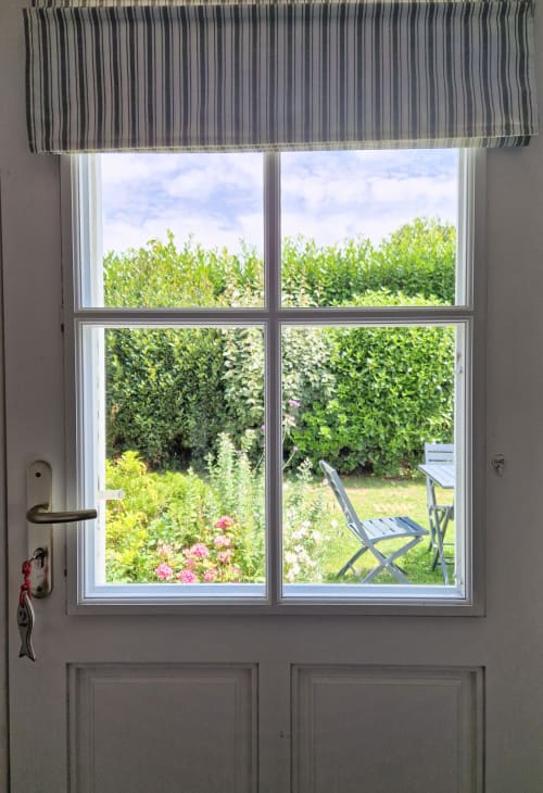 Vue sur le jardin depuis la fenêtre de la Suite Familiale aux Chambres du Keriolet, La Trinité sur Mer, avec haies, fleurs roses et