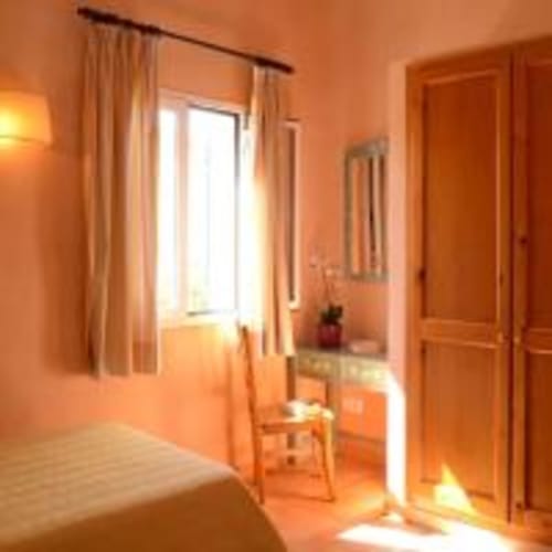 Acogedora habitación naranja en la villa Las Golondrinas con ventana, cortinas, puerta de madera y luz natural en Cap d'Artrutx