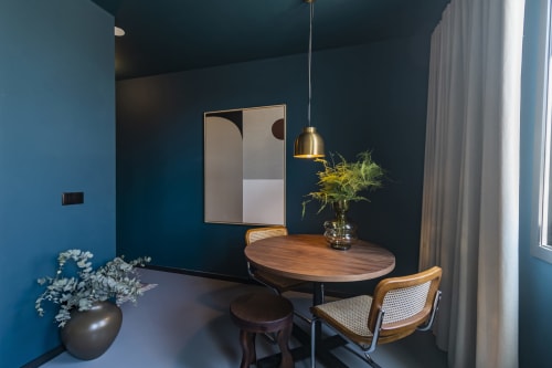 Moderna área de refeições do hotel Porto com paredes verde-azulado, mesa de madeira, cadeiras de ratã e luminária pendente