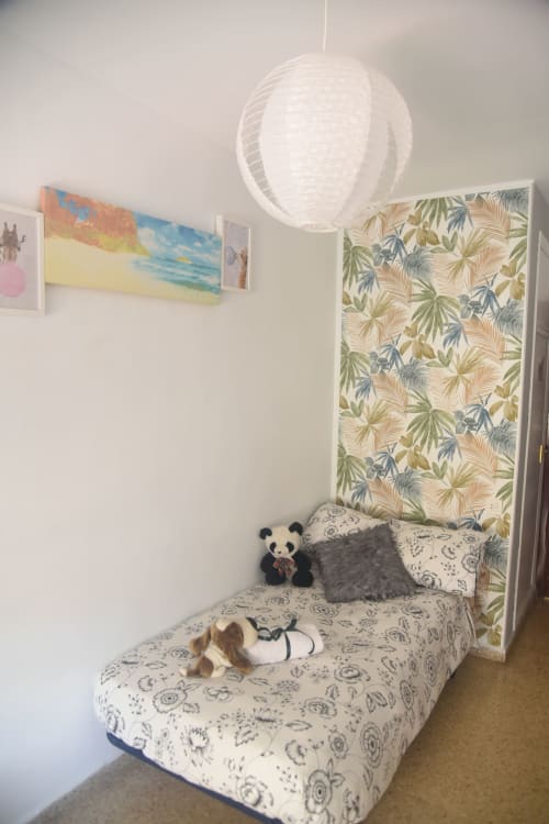 Cozy bedroom in Benavente apartment with bed, botanical wallpaper, pendant light, and plush toys