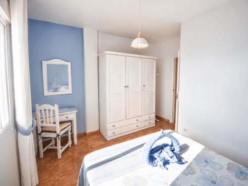 Bright bedroom in Cuevas del Almanzora apartment with blue accent wall, white wardrobe, and sea views