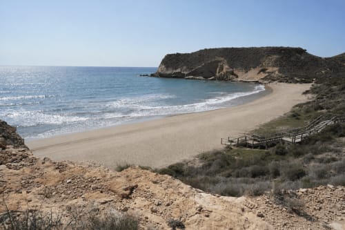 Scenic sandy beach cove with turquoise waters and rocky cliffs at Apartamentos El Calón Playa, Cuevas del Almanzora Spain