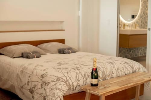 Chambre élégante aux Gîtes Saint Valéry-en-Caux avec bouteille de champagne sur banc bois, appartement vue mer en Normandie