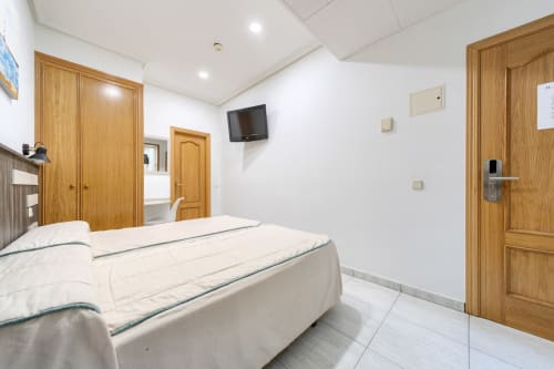 Habitación doble con dos camas en Hostal El Molino en Collado Villalba, con puertas de madera y televisión