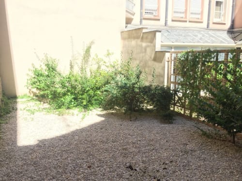 Jardin de cour partagé à l'appartement Le Paillot de Montabert à Troyes avec terrasse en gravier et végétation luxuriante