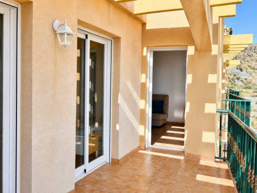 Sunny terrace at Apartamentos El Calón Playa with sea views, sliding glass doors, and coastal landscape in Cuevas del