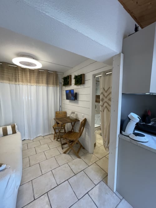 Appartement marina à Cap d'Agde avec table à manger, lit, cuisine et équipements modernes incluant TV et ventilateur
