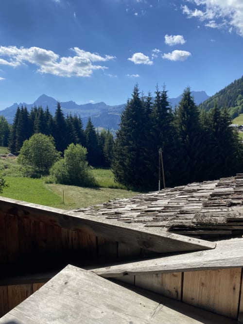 Terrasse en bois dominant la forêt alpine et les montagnes lointaines à La Ferme des Georgières, Notre-Dame-de-Bellecombe