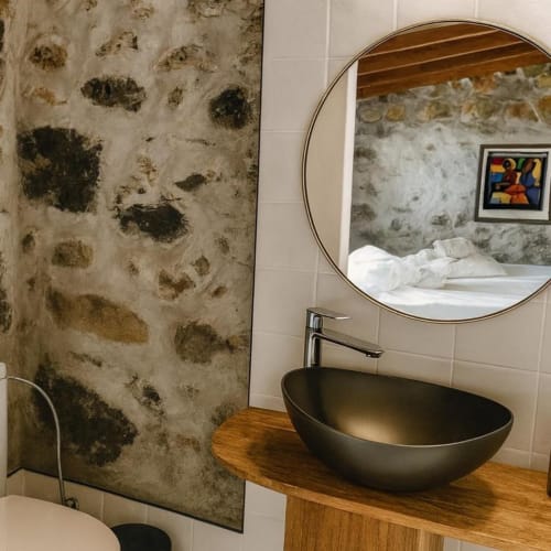 Cuarto de baño moderno en villa Nexus en la rural La Palma con lavabo negro tipo vasija, espejo redondo y pared dañada por moho