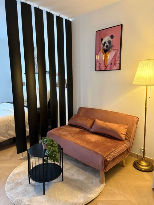 Lounge élégant et confortable au Paradis Des Logis : canapé terracotta, rideaux rayés noirs, œuvre panda et dorures