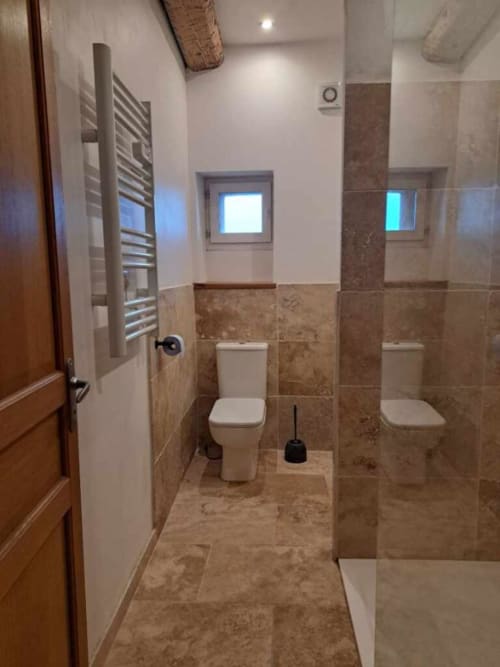 Salle de bains moderne dans l'appartement Chez Laure & Marc avec toilettes doubles, carrelage, radiateur sèche-serviettes et petites fenêtres