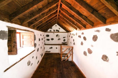 Dormitorio histórico con vigas de madera en Casa 1820 Rural La Palma, paredes blancas, muebles rústicos y vistas al jardín