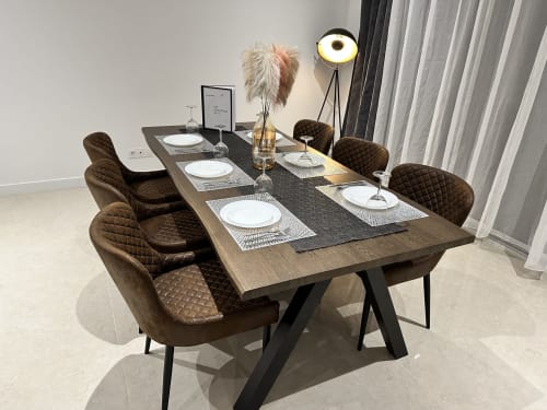 Salle à manger moderne aux Gîtes Les Camélias avec table dressée, chaises capitonnées marron et rideaux donnant sur le jardin
