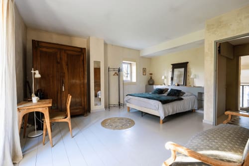 Chambre spacieuse au Mas F à Saint Rémy de Provence avec armoire en bois, lit, bureau et vue sur le jardin