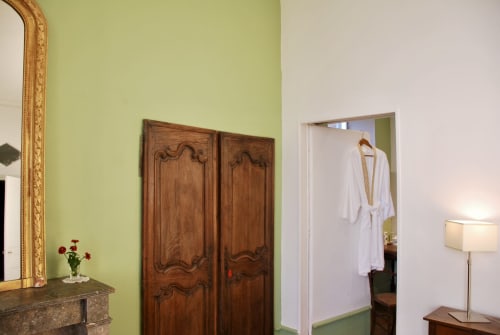 Chambre élégante du Château de Vaux Morvan aux murs vert citron, miroir orné, armoire en bois et peignoir blanc