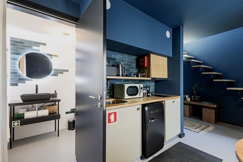 Estúdio duplex moderno Benefit Collection Porto com paredes azuis, kitchenette equipada e banheiro redondo