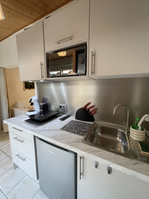 Cuisine moderne de l'appartement La Montagnette à Cap d'Agde avec armoires blanches, évier inox, micro-ondes et marbre