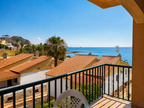 Balcony view of Mediterranean sea from Apartamentos El Calón Playa, Cuevas del Almanzora, with terracotta roofs and palm