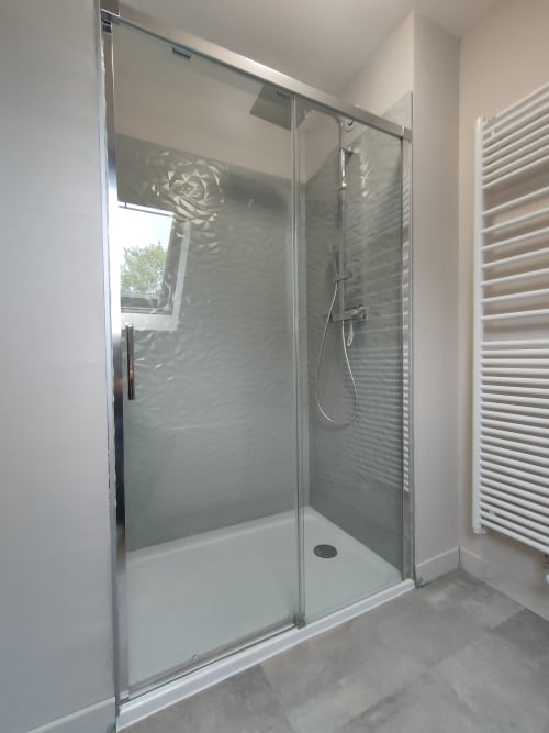 Douche vitrée moderne avec pomme de douche pluie et vasque en carrelage blanc dans une salle de bain de cottage