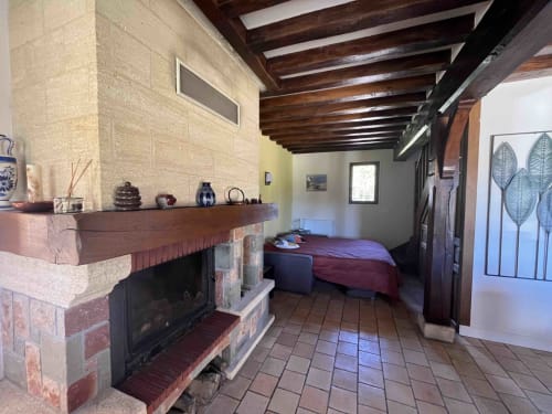 Chambre rustique du Domaine du Verger en Auge avec cheminée, poutres apparentes et lit, Normandie