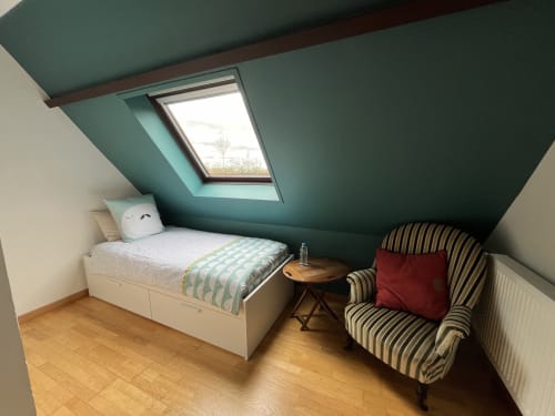 Chambre douillette sous les toits avec plafond mansardé, velux, lit blanc, fauteuil rayé, parquet au Domaine du Verger en Auge