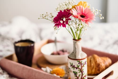Gerberas de colores en un jarrón decorativo sobre una bandeja de desayuno en el Hotel Santorini Belgrade