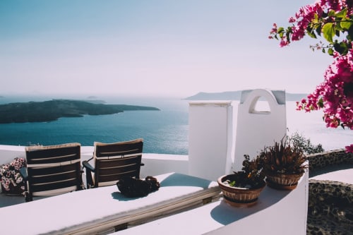 Suite Imperial Santorini con vista al mar, terraza blanca, tumbonas, flores magenta y el mar Egeo de fondo