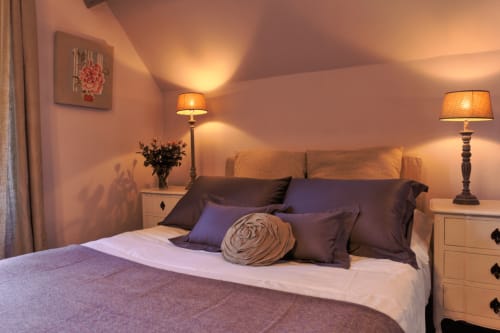 Chambre élégante au Petit Manoir de Kériolet à Concarneau avec lit queen, coussins décoratifs, lampes de chevet et jardin