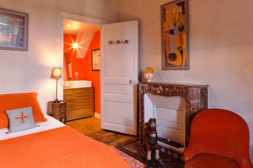 La chambre Irina du Petit Manoir de Kériolet à Concarneau : literie orange éclatante, mobilier en bois et style moderne