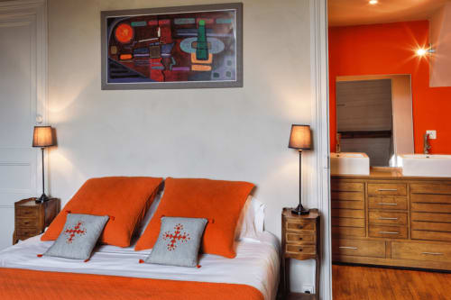 Chambre moderne du Petit Manoir de Kériolet avec literie orange, mobilier en bois et art contemporain à Concarneau