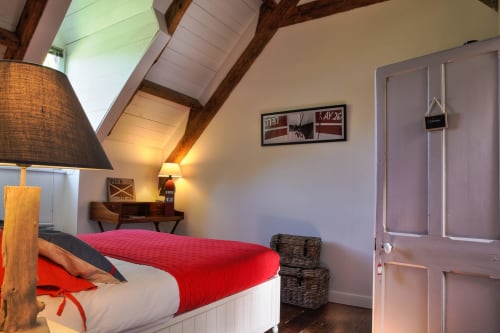 Chambre cosy sous les toits au Petit Manoir de Concarneau, avec literie rouge, poutres apparentes, lucarne et bureau