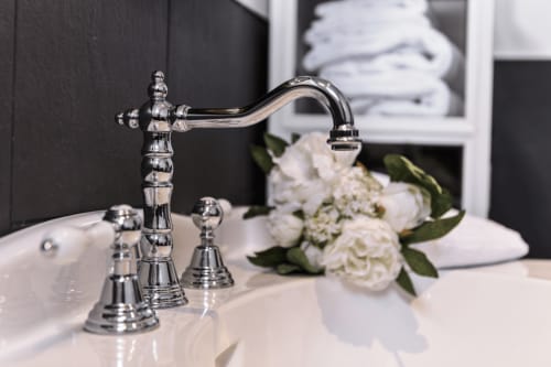 Élégant robinet chromé de salle de bain avec fleurs blanches au Petit Manoir de Kériolet à Concarneau