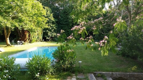 Jardin luxuriant avec piscine bleue, arbres en fleurs et pelouses verdoyantes au Petit Manoir de Kériolet, Concarneau