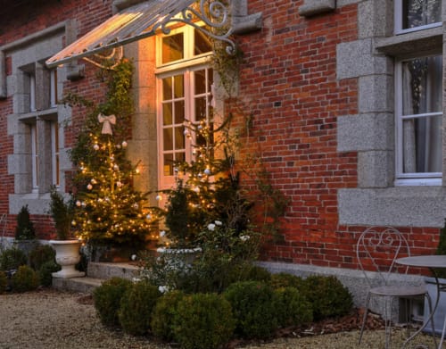 Entrée festive du Gîte Le Petit Manoir de Kériolet à Concarneau, décorée de lumières de Noël étincelantes et ornementations dorées